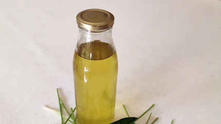 Vor einer Glasflasche mit Öl liegen Bärlauchblätter und -blüten