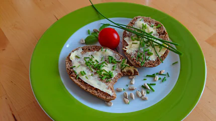Zwei dünne Scheiben Brot mit Butter und Schnittlauch.