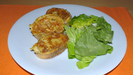 Drei Scheiben Eierbrot liefen auf einem Teller mit Blattsalat. Das Bundaschkenja wurde schön braun gebraten.