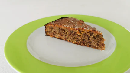 Ein Stück Datteltorte aus grob gehackten Mandeln, Haselnüssen und Datteln. Es ist mit einer halben Dattel verziert.