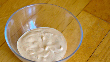 Eine Schale mit zartroter Dönersauce mit Mayonnaise, Paprikapulver und Dill.