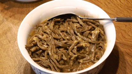 Eine große Schale mit dürren, grünen Bohnen mit einer sämigen Sauce aus Zwiebeln und Mehlschwitze.