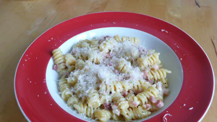 Ein Teller Fusilli mit einer Sauce aus Eiern und Speckwürfeln, bestreut mit Parmesan.