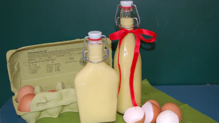Zwei kleine, hübsche Flaschen mit Eierlikör. Eierschalen liegen daneben.