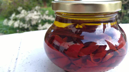 Ein Einmachglas mit Chilistreifen, die in Olivenöl eingelegt sind.