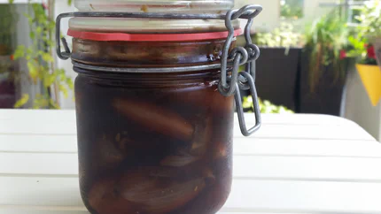 Ein Einmachglas mit ganzen Schalotten in Sherry, Whisky und Balsamico.