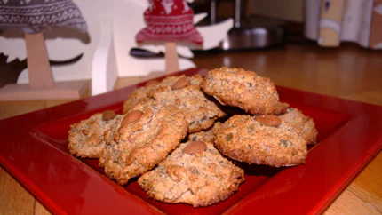 Eine Schale mit Elisenlebkuchen mit jeweils einer ganzen Mandel darauf, umgeben von Weihnachtsdekoration.