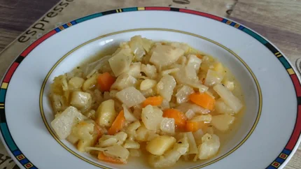 Ein tiefer Teller mit Kartoffel-, Lauch-, Paprika- und Kohlrabiwürfeln in einer Brühe.
