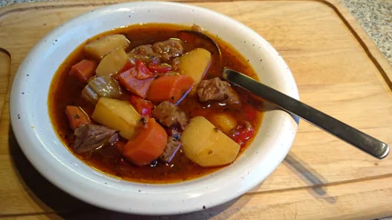 Rindfleisch-, Kartoffel- und Paprikawürfel liegen in einer roten Gulaschsuppe.