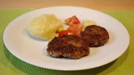 Zwei braun gebratene Hackfleischküchle mit Senf und Kartoffelsalat.