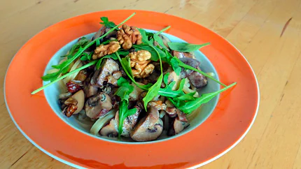 Spaghetti mit gerösteten Walnüssen, Champignons und Rucola in einem tiefen Teller.