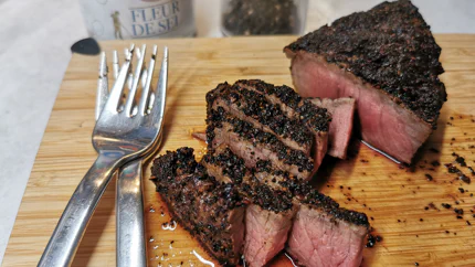Ein Steak mit einem Mantel aus gemahlenem Kaffee liegt auf einem Brett. Es sind bereits Streifen abgeschnitten - das Innere ist nocht zartrosa.