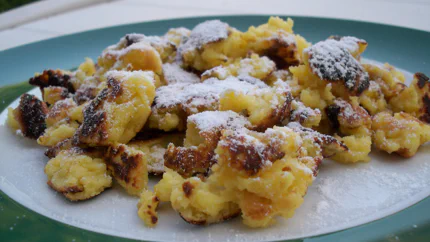 Eine Portion Kaiserschmarrn auf einem Teller. Sie ist nur mit Puderzucker bedeckt.