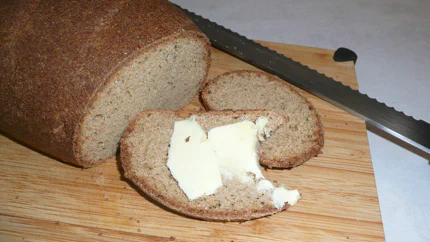 Ein Laib Brot mit dunkelbrauner Kruste, von dem zwei Scheiben abgeschnitten wurden.