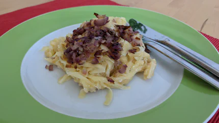 Eine Portion Kässpätzle mit Röstzwiebeln aus roten Zwiebeln.