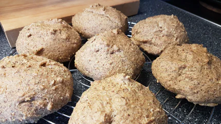 Sieben hellbraune, ketogene Brötchen auf einem Blech.