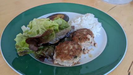 Zwei Hackfleischküchle mit Blattsalat, Reis und Aubergine.
