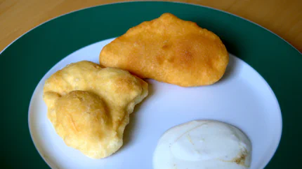 Zwei dicke Langosch-Fladen liegen auf einem Teller mit Joghurt-Dip mit Knoblauch.