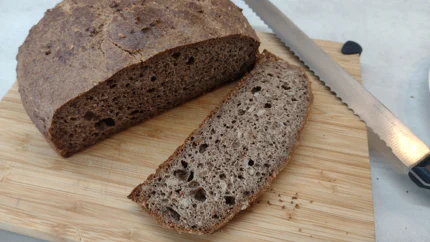 Ein runder Laib Brot mit verschieden großen Löchern, von dem eine Scheibe abgeschnitten wurde.