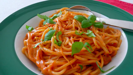 Eine Portion Spaghetti mit einer zähflüssigen Sauce aus Mozzarella und Tomaten, mit frischem Basilikum garniert.