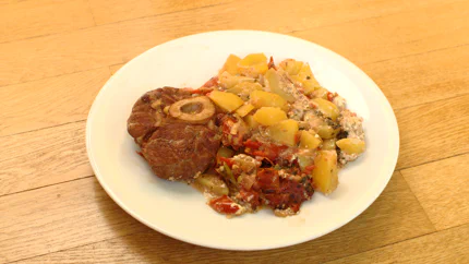 Eine angebratene Rinderbeinscheibe mit Gemüse und Kartoffeln.