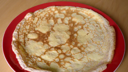 Ein hellbraun gebackener Pfannkuchen auf einem Teller.
