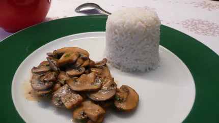 Eine Sauce aus dünnen Champignonscheiben, Sahne, Petersilie und schwarzem Knoblauch. Dazu gibt es Reis, der in eine Kuppelform gedrückt wurde.
