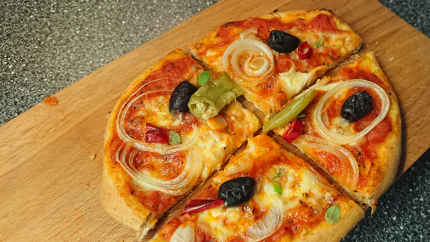 Eine goldbraun gebackene, ovale Pizza mit Mozzarella, Zwiebeln, Tomaten und Pepperoni.