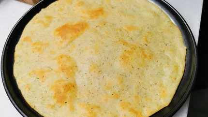 Ein ausgewallter und vorgebackener Pizzateig mit Mozzarella und Kräutern.