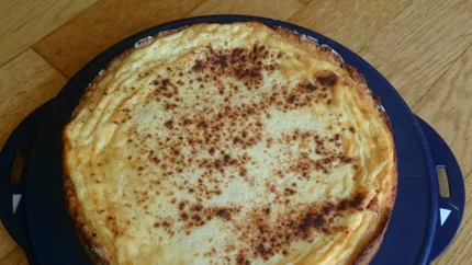 Ein runder Rahmkuchen mit braunem Rand und mit Zimt bestreut.