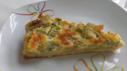 Ein Stück Rhabarber mit einem dünnen Boden aus Mürbteig und einem Belag aus Rhabarberstücken, Eiern und Quark.