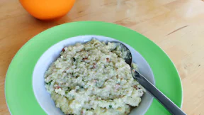 Ein Teller mit sämigem Risotto, in dem Speckwürfel und schwarze Pünktchen vom Trüffel sind.