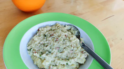 Ein Teller mit sämigem Risotto, in dem Speckwürfel und schwarze Pünktchen vom Trüffel sind.