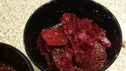 Salat aus groben Scheiben Rote Beete mit Kümmel, Essig und Öl in einer Schale.