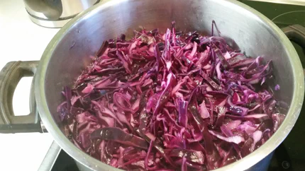 Ein hoher Topf mit noch rohem Rotkraut, aus dem Dampf aufsteigt.