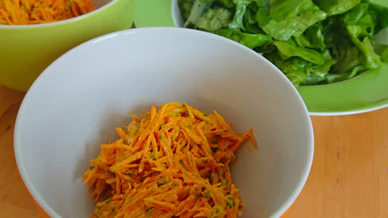 Zwei Schalen mit Salat aus geraspelten Rüben, Joghurt, Curry und Petersilie. Dahinter steht ein Teller mit Blattsalat.