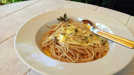 Ein großer Teller mit Spaghetti und einer sahnigen Salbeisauce. Eine Spitze Salbei garniert schön den Rand des Tellers.