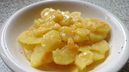 Eine Portion glänzende Kartoffeln liegen in einem Teller. Sie glänzen von der Sauce aus Brühe, Paprikapulver, Essig und Öl.