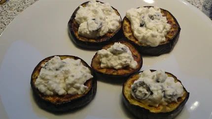 Fünf gegrillte Auberginenscheiben mit einer Creme aus Schafskäse und schwarzen Oliven.
