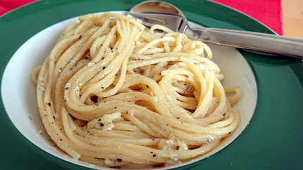 Eine Portion rund gedrehte Spaghetti mit Käse, scharzem Pfeffer und etwas Öl.
