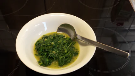 Eine Portion Spinat mit Sahne und Knoblauch als Beilage in einer weißen Schale mit Löffel.