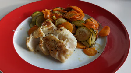 Ein gewürztes und angebratenes Kabeljaufilet mit einer Portion Gemüse, das mit Kräutern und Verjus (Saft aus unreifen Trauben) abgeschmeckt wurde.