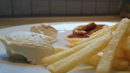 Ein großer Klecks Mayonnaise und Ketchup liegen neben Pommes auf einem Teller.