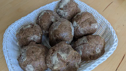 Acht dunkelbraune Vinschgauerle liegen in einem Brotkorb.