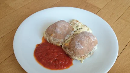 Zwei Vollkornbuchteln oder -brötchen auf einem Teller. Dazu gibt es Tomatensauce.