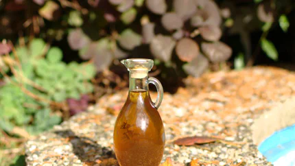 Eine hübsche Flasche in der Form eines Kruges mit goldenem Whisky-Kräuter-Likör steht auf dem steinernen Rand eines Gartenteiches.
