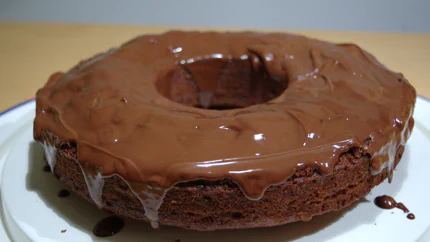Ein brauner Kuchen mit Kakao, Whisky und Rosinen mit viel Schokoladenguss, der noch an den Seiten herunterrinnt.