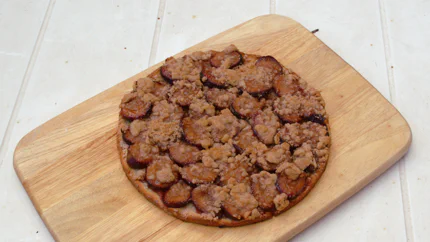 Ein runder Kuchen mit dünnem Hefeteig ohne Rand, auf dem die Zwetschgen ziegelartig geschichtet und mit Sträuseln bedeckt sind.