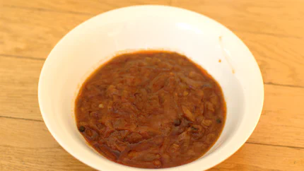 Eine Schale mit dickflüssiger Sauce aus Zwiebeln, und ganzen Pfefferkörnern.