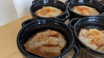 Vier Schälchen mit Henkeln, in denen auf einer Zwiebelsuppe mit Käse überbackener Toast schwimmt.